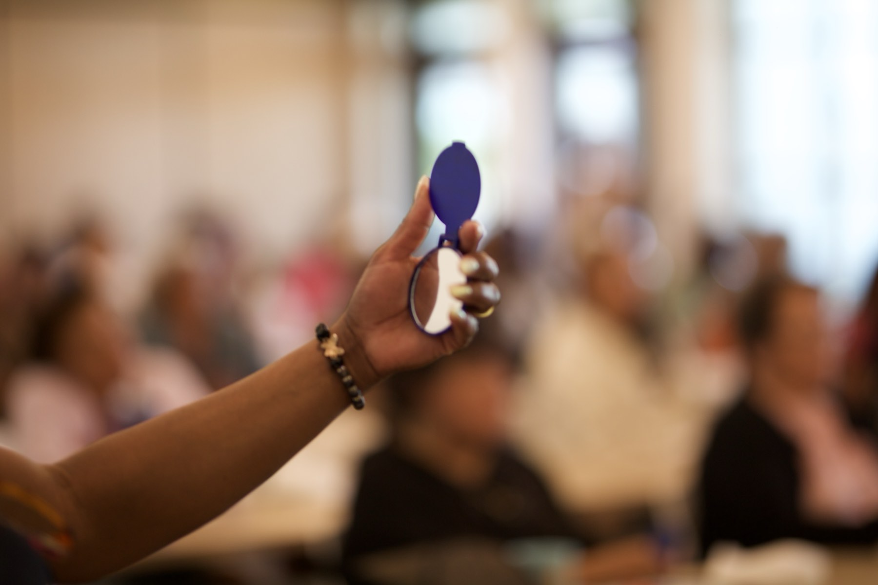 A raised hand during a session, the room soft behind